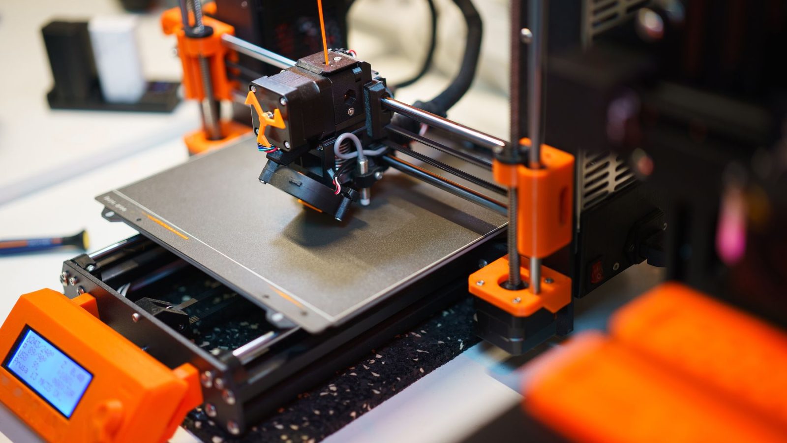 Detailed view of a 3D printer creating an object with orange components