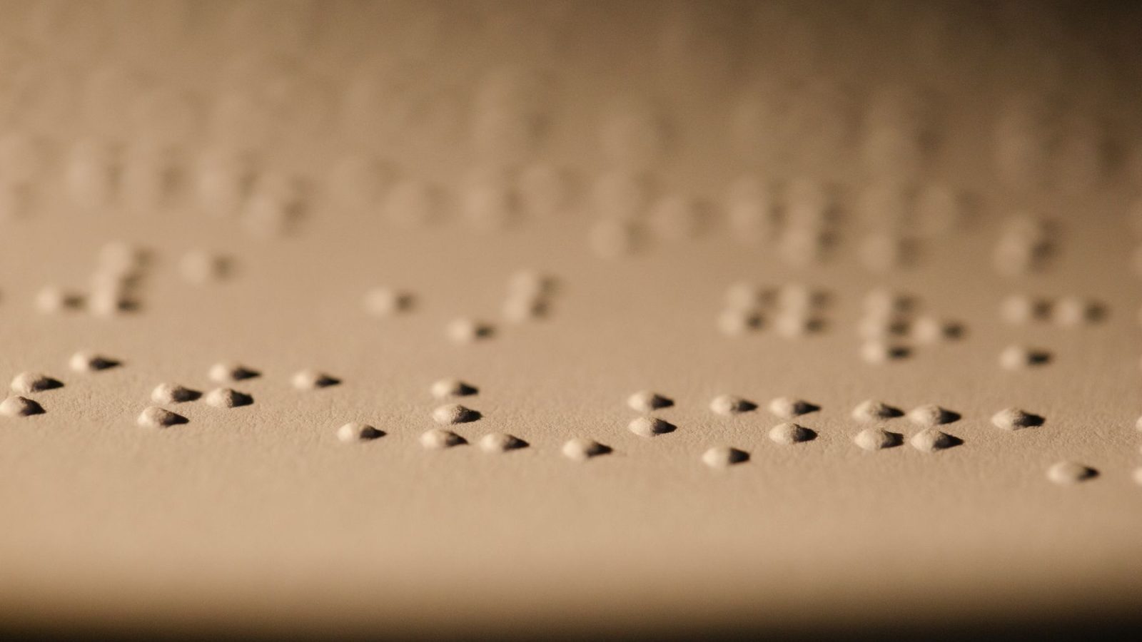 Makroaufnahme von Braille-Punkten, die in Papier geprägt sind, als Beispiel für taktiles Lesen bei Sehbehinderung