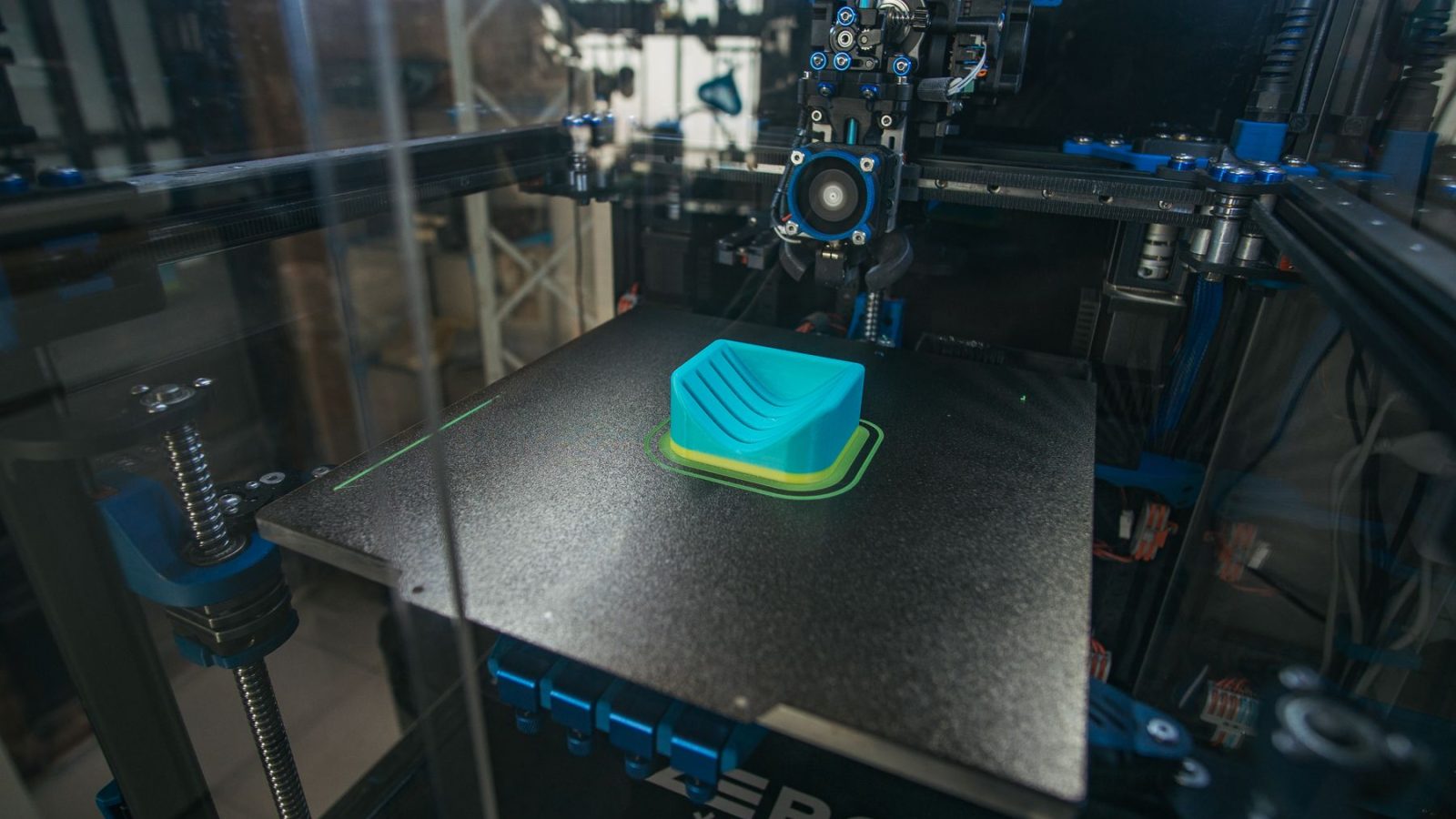 Nahaufnahme eines 3D-Druckers, der in einer Industrieumgebung ein Kunststoffobjekt druckt