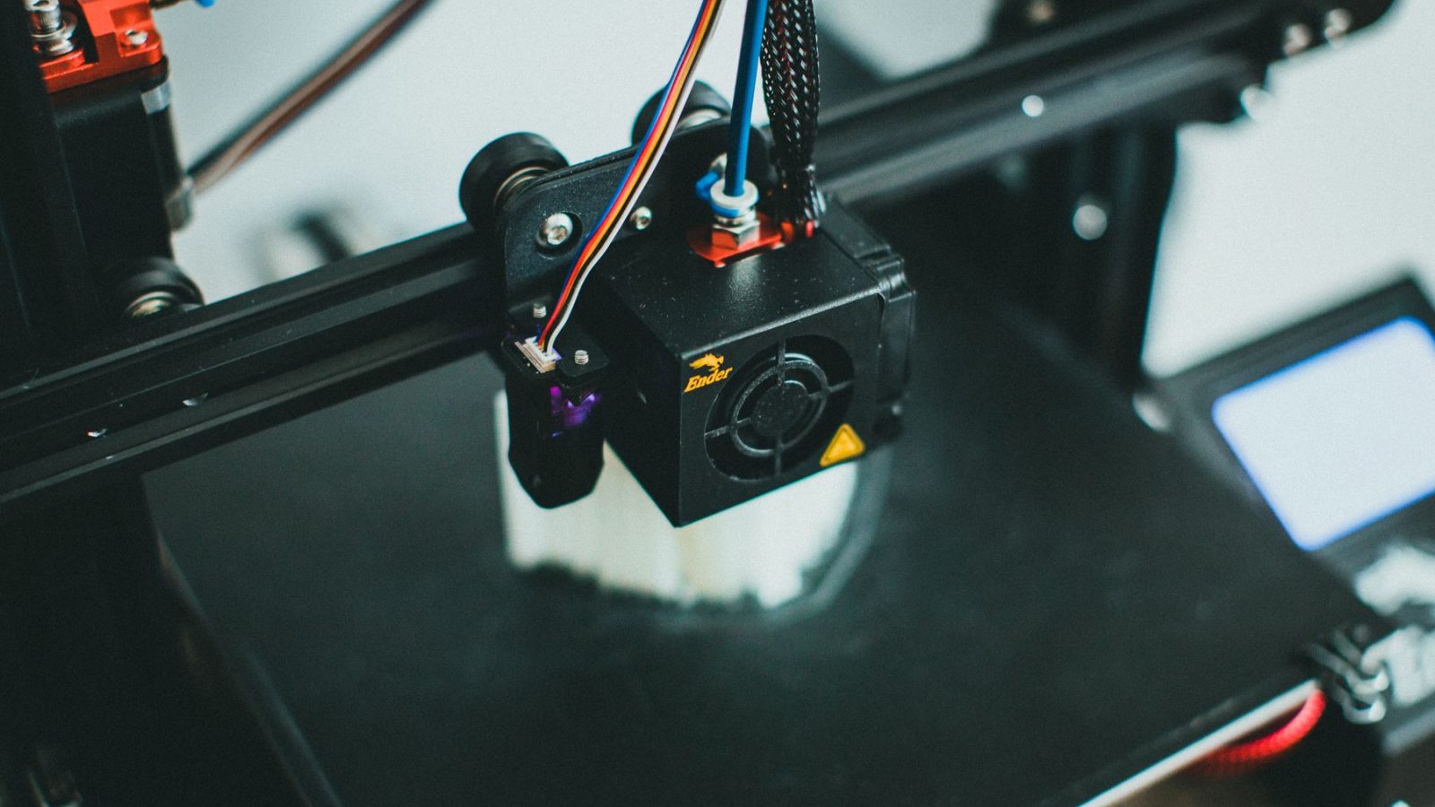 Dettaglio di una stampante 3D che realizza un oggetto, con la ventola di raffreddamento e la testina di stampa in primo piano