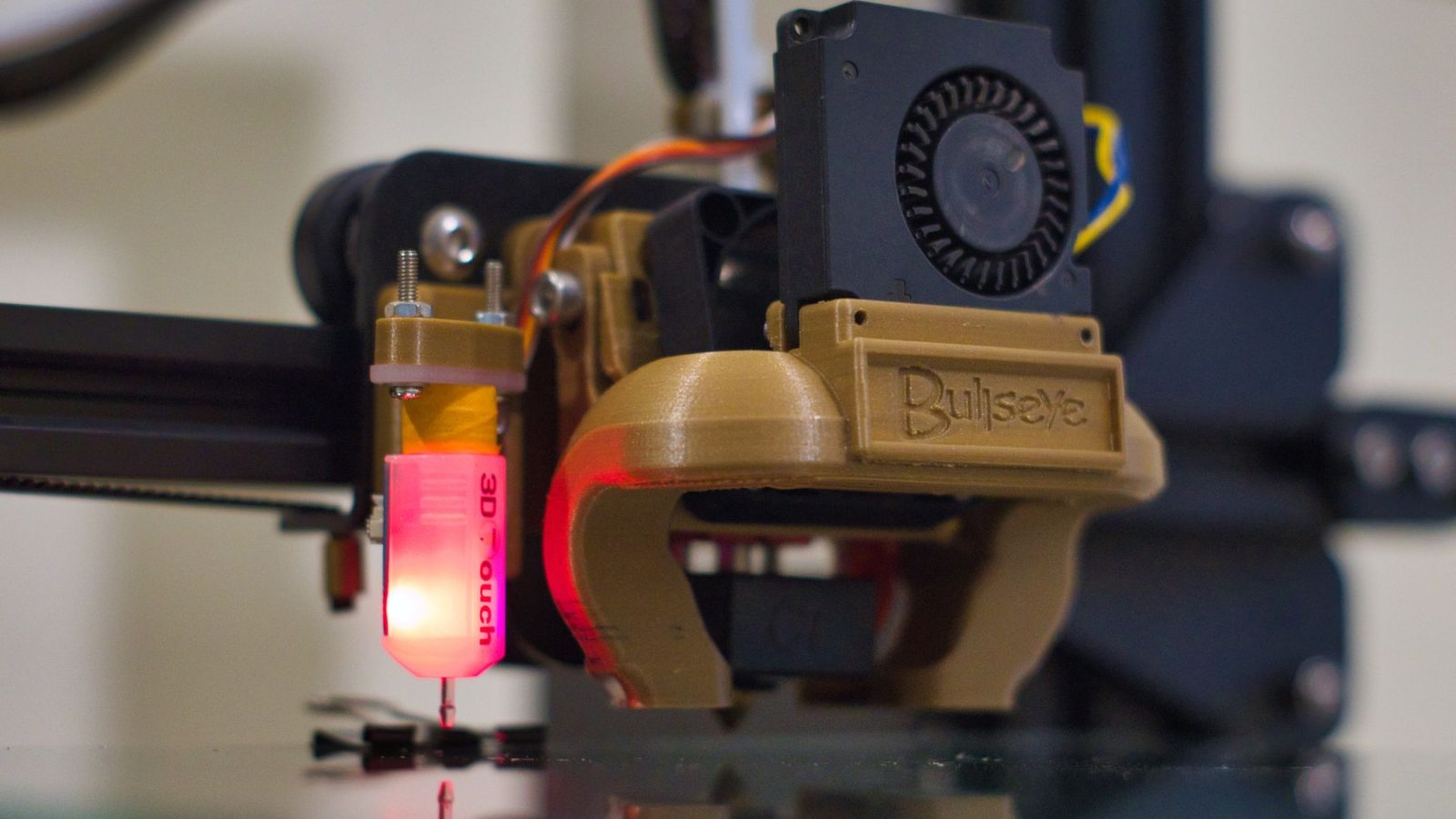Részletes felvétel egy 3D nyomtató fúvókájáról működés közben, műhelykörnyezetben