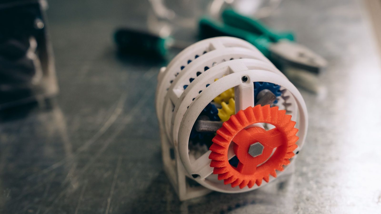 Nahaufnahme eines 3D-gedruckten Zahnradmechanismus auf einer Werkbank aus Metall, die Innovation und Technik hervorhebt