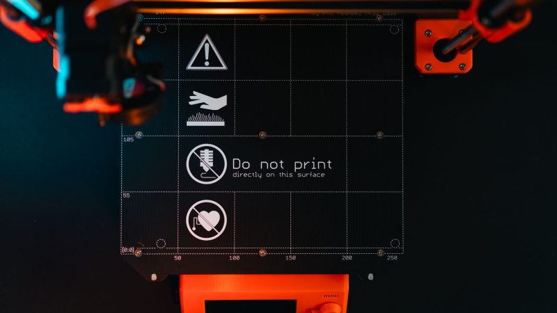 3D-Drucker-Druckplatte mit Warnsymbolen in einer Werkstatt mit Hightech-Ausrüstung