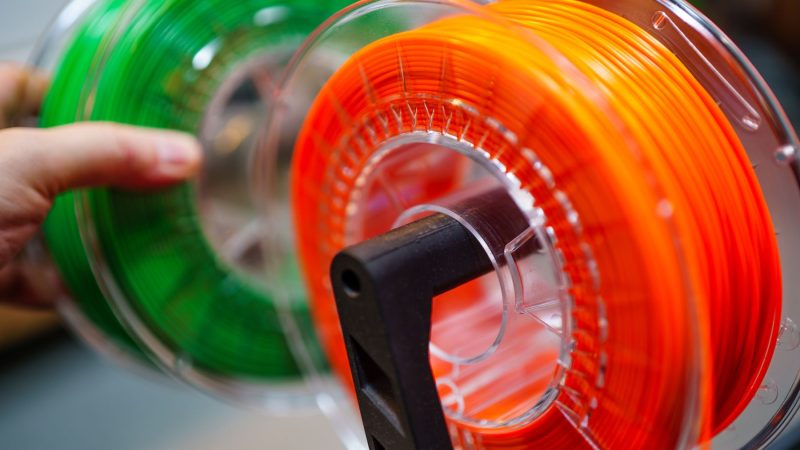 Leuchtend orangefarbene und grüne 3D-Drucker-Filamentspulen für innovative Fertigungszwecke