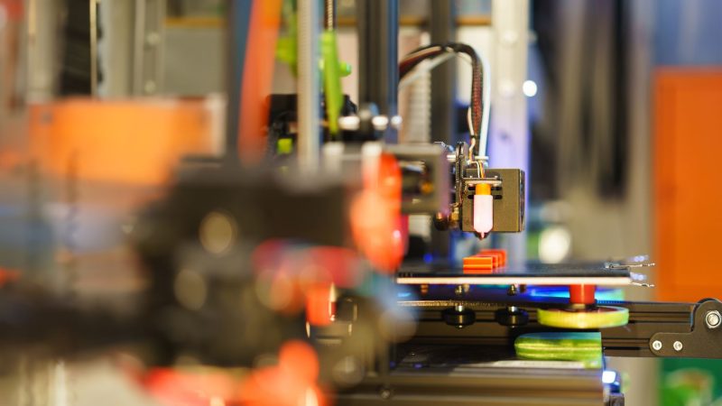 Detailansicht eines 3D-Druckers im Betrieb, der einen farbigen Prototyp druckt