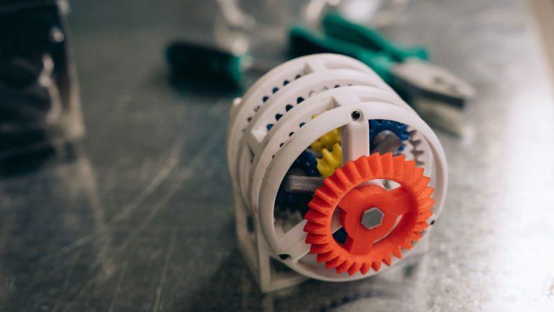 Nahaufnahme eines 3D-gedruckten Zahnradmechanismus auf einer Werkbank aus Metall, die Innovation und Technik hervorhebt